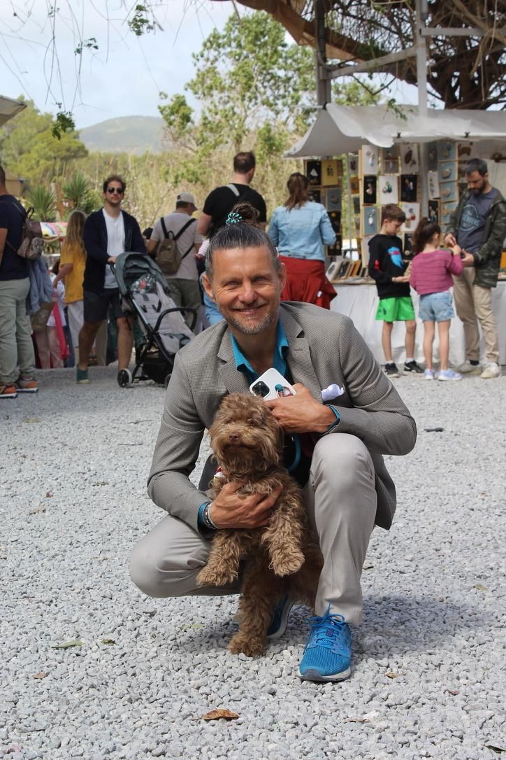 Hundecoach im Anzug mit kleinem braunem Hund auf einem Markt auf Mallorca.